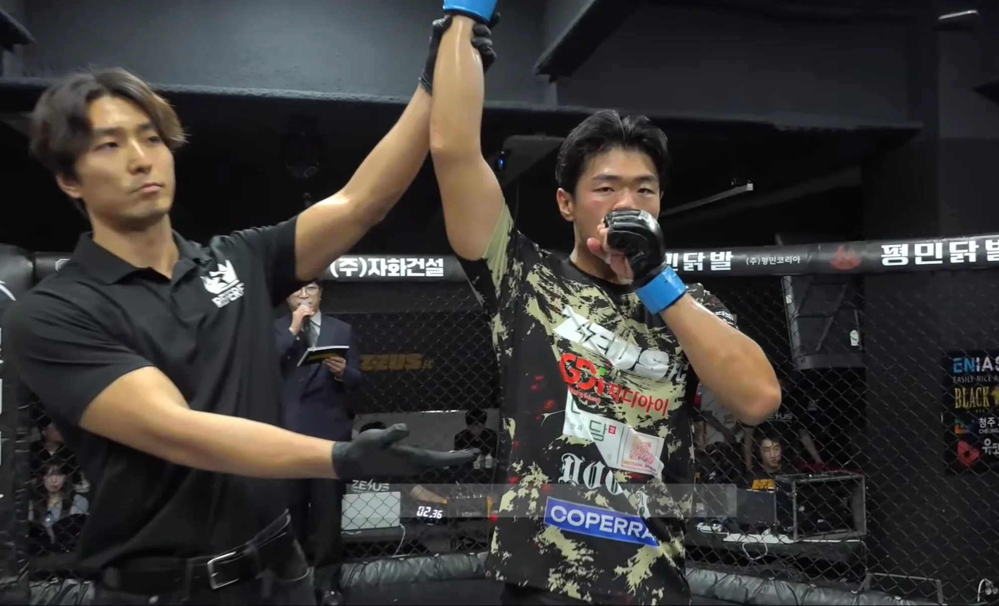 The referee raises Kwon Ji-hu's hand to declare the win, with the COPERRAL sponsor patch on his shirt
